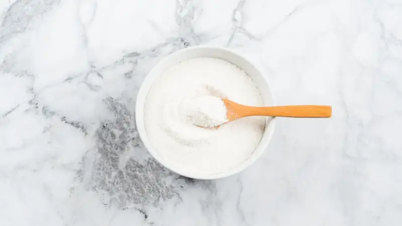 Schüssel mit weißem Pulver, das Kollagenpeptide enthält. Die Wirkung von Kollagenpeptiden ist vielfältig.