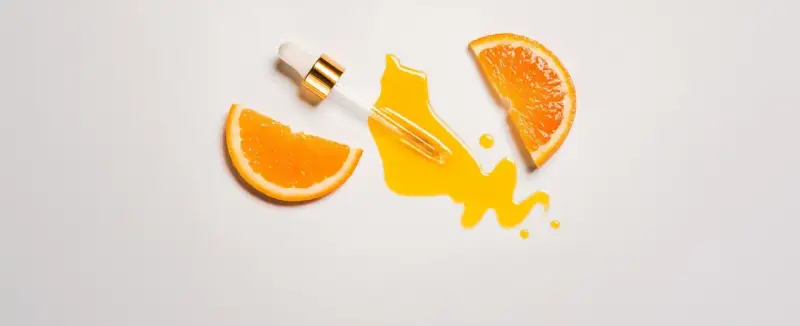 Orangenscheiben und ein Pipetten-Serum auf weißem Hintergrund. Vorsicht bei zu viel Vitamin C für die Haut, es kann Reizungen verursachen.